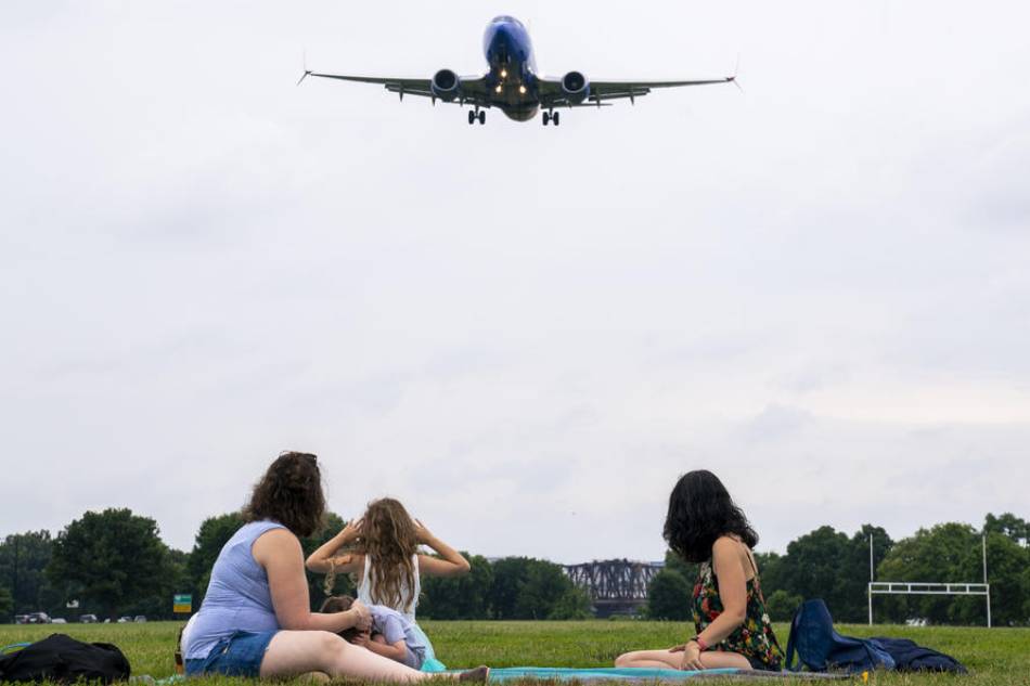 Plane watchers look on as a jet comes in for a landing at Ronald Reagan Washington National Airport in Arlington, Virginia, USA, 27 June 2022. EPA-EFE/SHAWN THEW