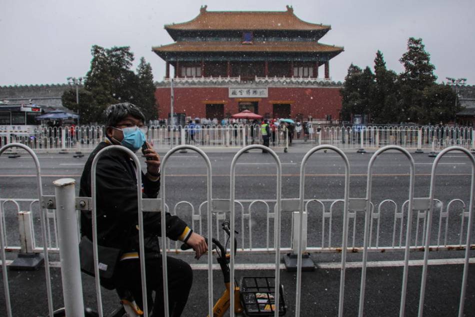 A man uses his mobile phone outside the Forbidden City during a snowfall in Beijing, China, 17 March 2022. Wu Hong, EPA-EFE