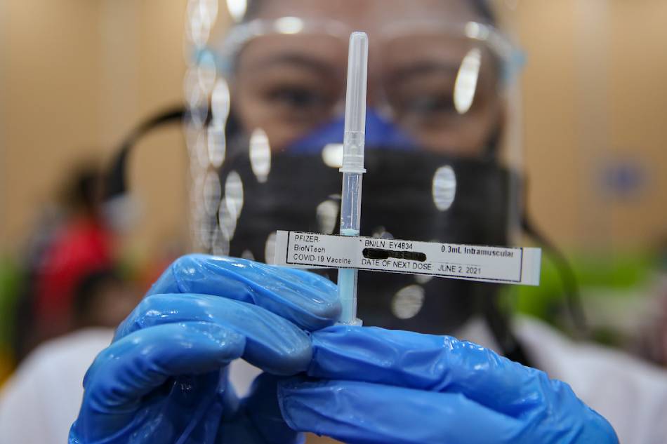 A health worker shows the syringe containing the COVID-19 vaccine of Pfizer BioNTech during its rollout inside the Makati Medical Center on May 12, 2021. George Calvelo, ABS-CBN News
