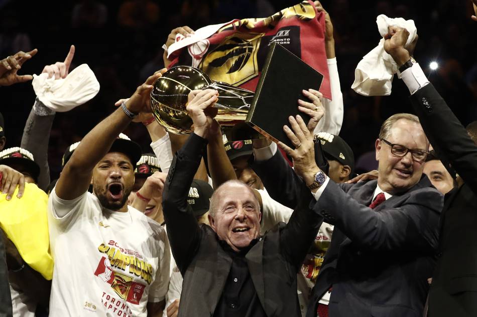 Toronto Raptors player Norman Powell (L) on stage with Larry Tanenbaum (C) and George Cope (R) members of the ownership group holding up the Larry O