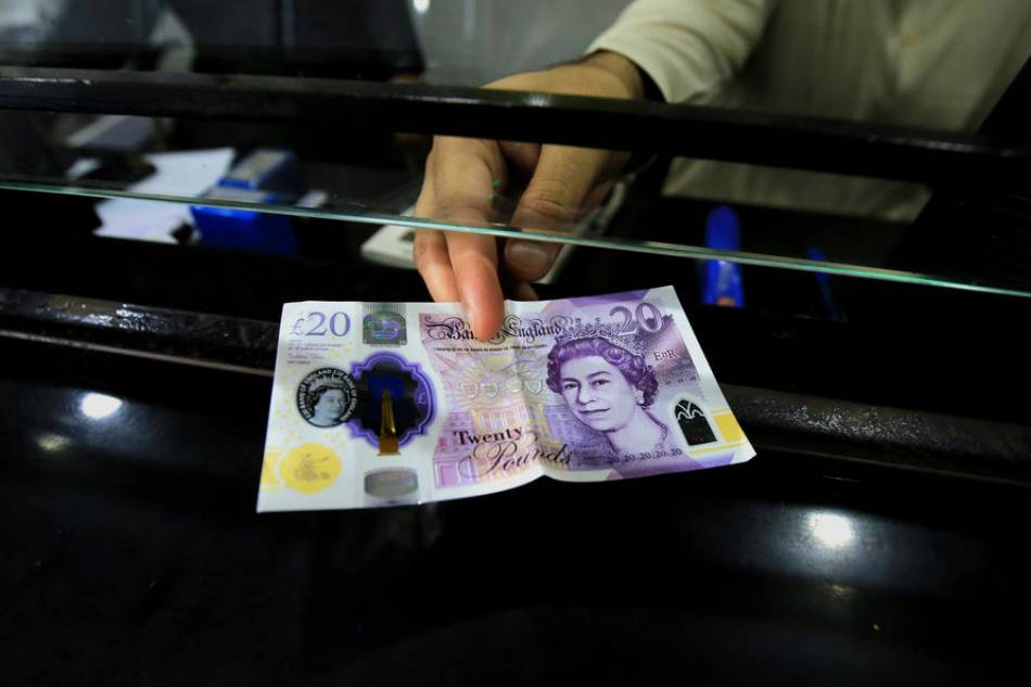 A worker holds a Pound sterling banknote at a money exchange company in Peshawar, Pakistan, 23 September 2022. The British pound fell more than 2 percent against the Dollar on 23 September after the British government announced a radical economic plan to boost growth. EPA-EFE/ARSHAD ARBAB