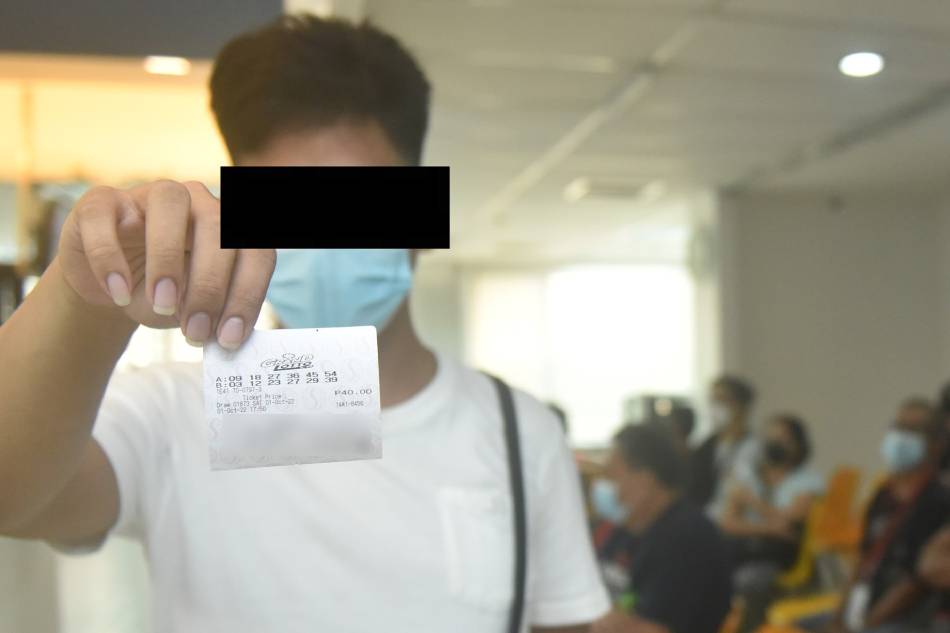 One of the winners of the 6/55 Grand Lotto draw on Oct. 1 shows his ticket on Oct 3, 2022 at the Philippine Charity Sweepstakes Office in Mandaluyong City. Photo from the PCSO Facebook page.