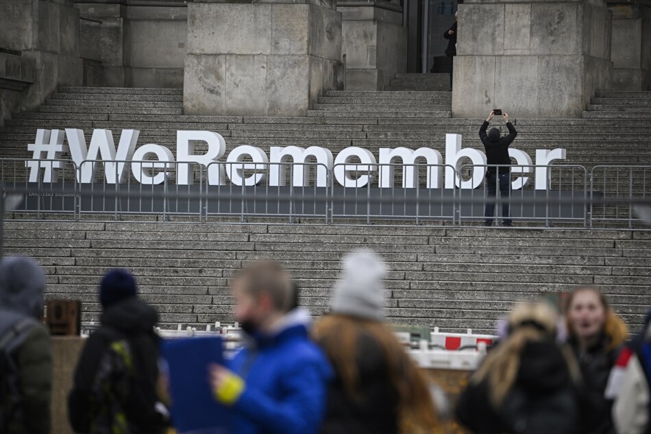 Visitors stand in front of the lettering #WeRemember installed on the stairs leading to the Reichstag building hosting the German lower House of parliament, the Bundestag, on January 24, 2023 in Berlin as part of the ceremonies for the International Holocaust Remembrance Day held on January 27. Tobias Schwarz / AFP