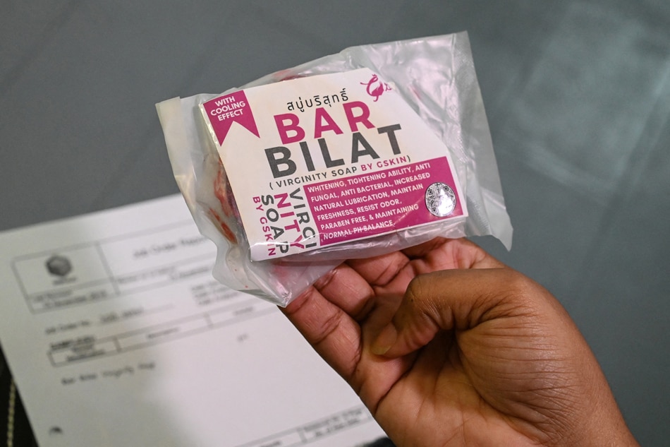 This photo taken on Feb. 13, 2023 shows a person holding a packet of Bar Bilat, a brand of 'virginity soap' not approved by the Philippine Food and Drug Administration and advertised on social media platforms with bogus claims it can be safely used to 'tighten' vaginas, inside a laboratory at the Ateneo de Manila University in Quezon City, Metro Manila. Jam Sta. Rosa, AFP