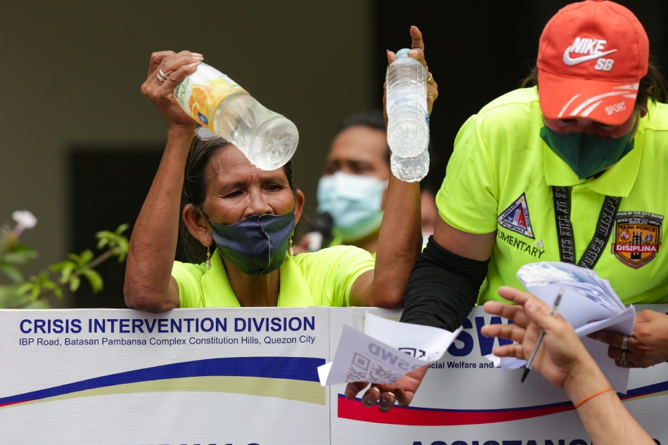Government employees hand out cups of drinking water as people fall in line at the Department of Social Welfare and Development (DSWD) central office in Quezon City on August 20, 2022. George Calvelo, ABS-CBN News/file