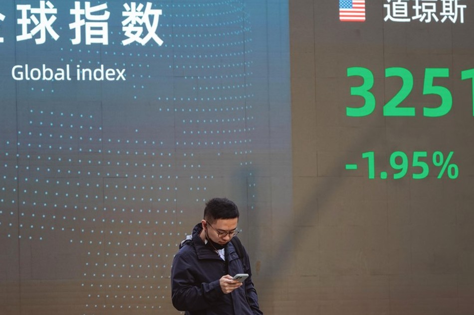 A man walks past a display showing the latest stock exchange data, in Shanghai, China, 10 November 2022. EPA-EFE/ALEX PLAVEVSKI/FILE