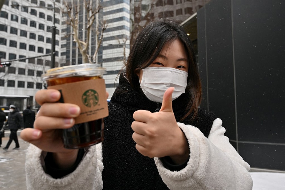 This picture taken on Jan. 26, 2023 shows office worker Jeong Jae-won posing with an iced Americano during an interview with AFP on a street in Seoul. Jung Yeon-je, AFP