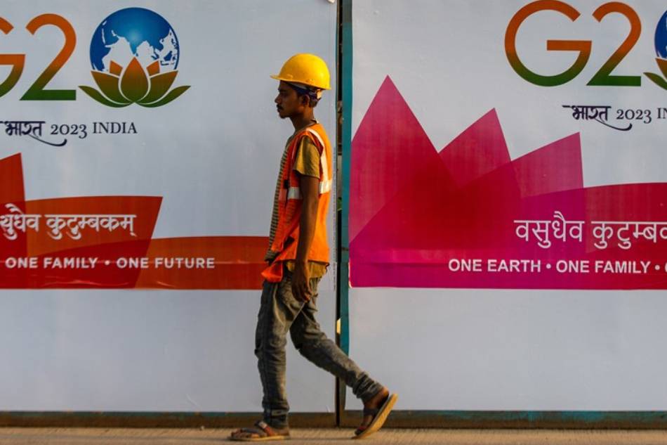 A worker walks past a G20 poster on street of Mumbai, India, 12 December 2022. India officially assumed G-20 Presidency on 01 December 2022. EPA-EFE/DIVYAKANT SOLANKI