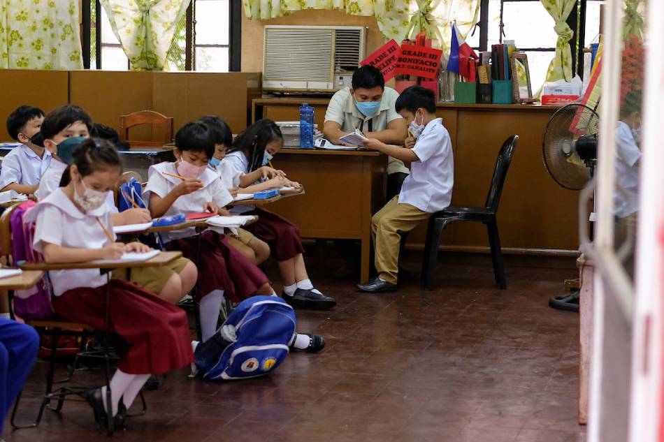 A teacher checks a student’s work inside the Aurora A. Quezon Elementary School in Manila on the first day of classes, August 22, 2022. George Calvelo, ABS-CBN News/File
