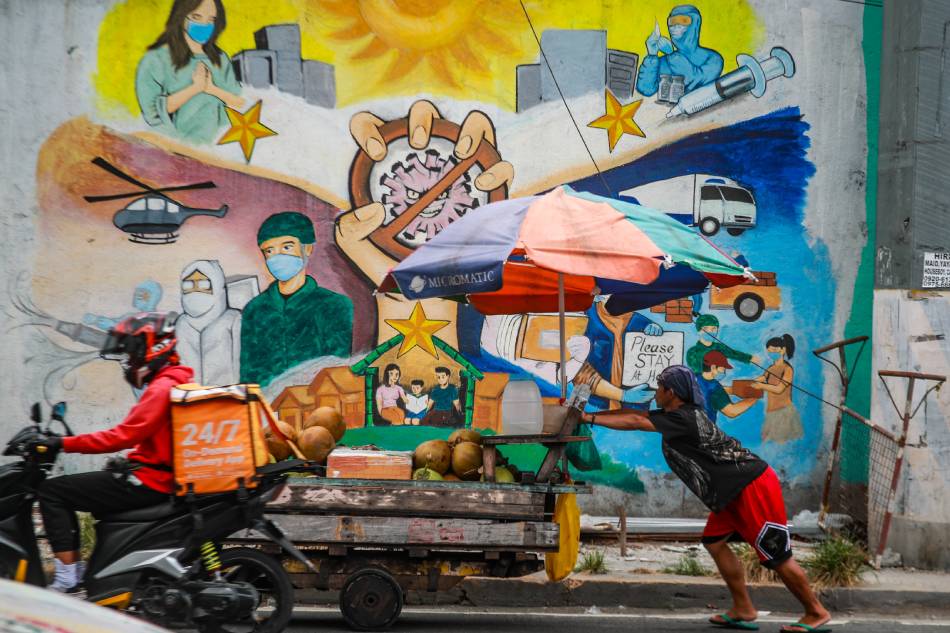 A vendor passes by a mural depicting the COVID-19 pandemic along Pedro Gil, Manila on May 10, 2023. Jonathan Cellona, ABS-CBN News