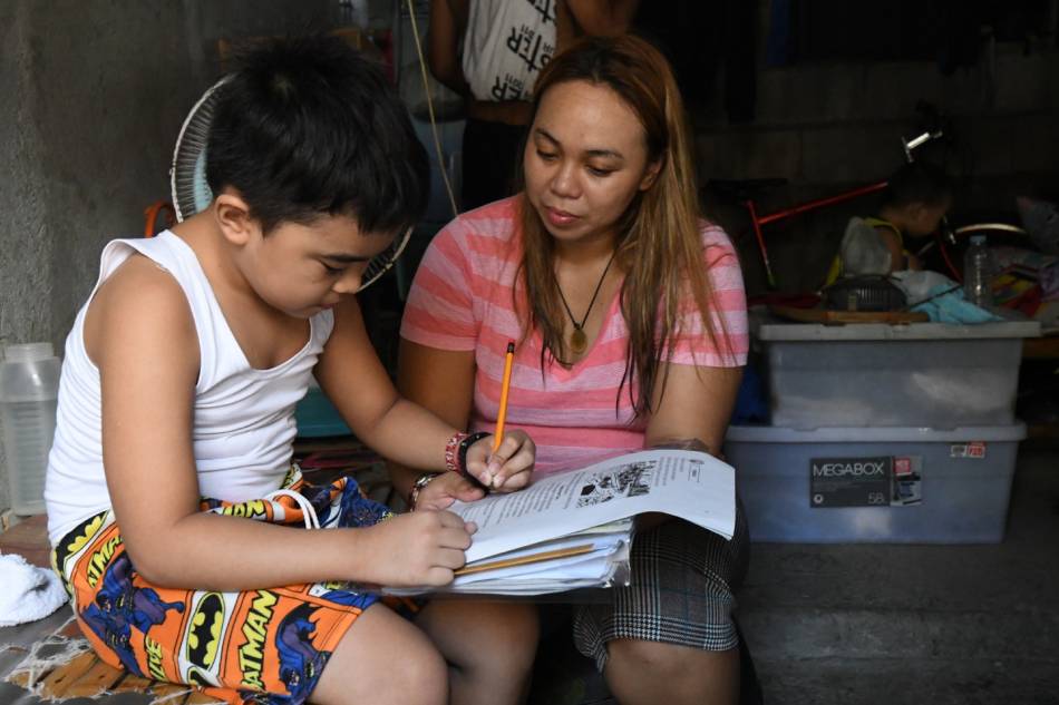 Snack store owner Evangeline Vidal guides her Grade 2 son Calix Jaden Aglibot through his learning module on Oct. 5, 2020. 