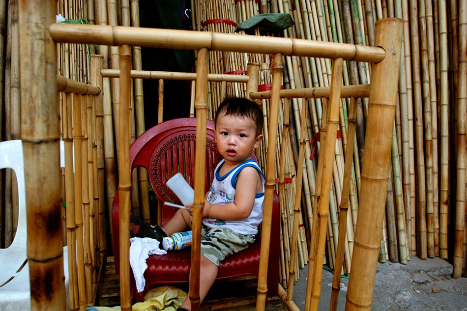 A baby boy peers out from a bamboo crib outside a shop selling bamboo in Hanoi, Vietnam, on November 10, 2006. Julian Abram Wainwright, EPA