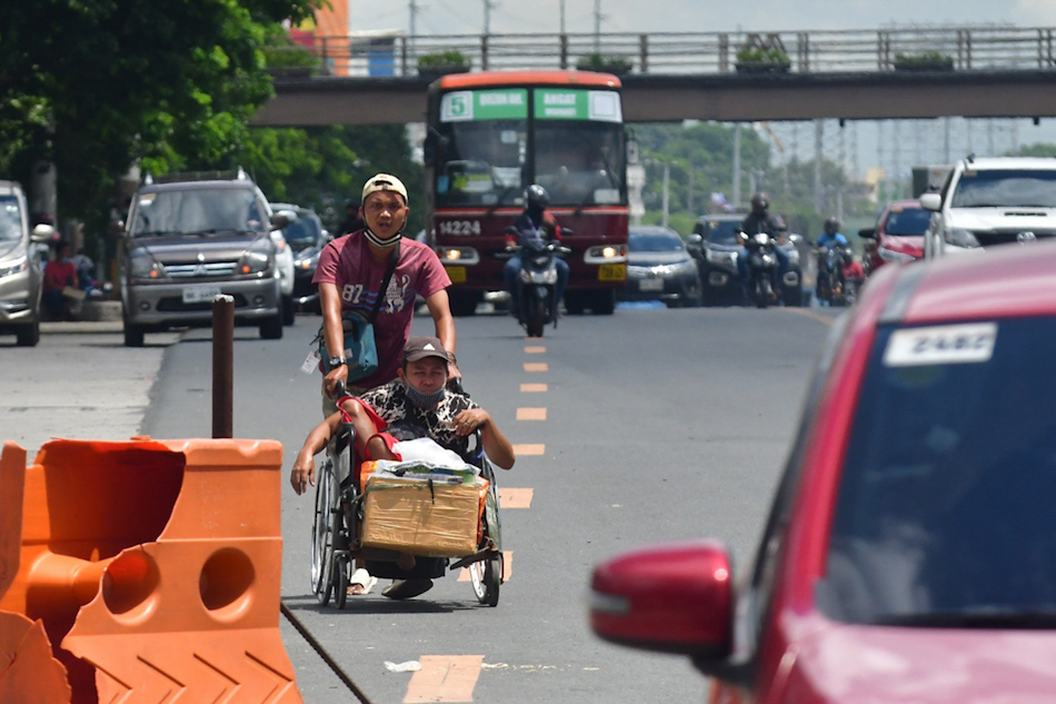 A man, assisted by his cousin, traverses Commonwealth Avenue in Quezon City on June 9, 2020 amid the general community quarantine. Mark Demayo, ABS-CBN News/file 