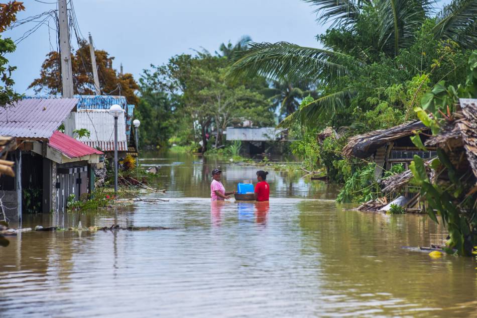 Residents wade through waist-deep water to reach their houses in a flooded area of Barangay Libertad, Abulug, Cagayan on July 27, 2023. Maria Tan, ABS-CBN News