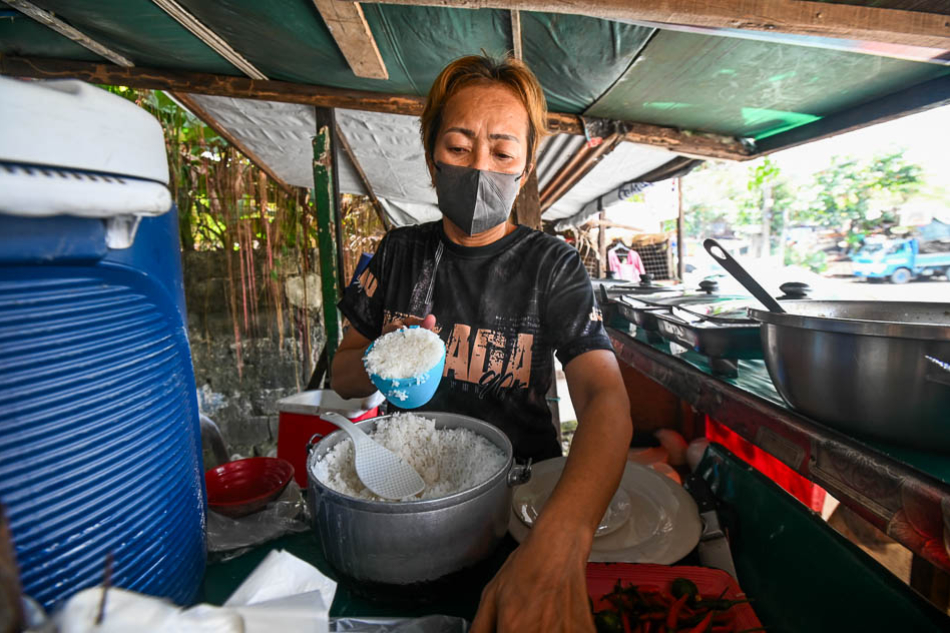 Janlee Almoete scoops cups of rice as she prepares to serve her customers inside her carinderia in Quezon City on November 10, 2023. Maria Tan, ABS-CBN News