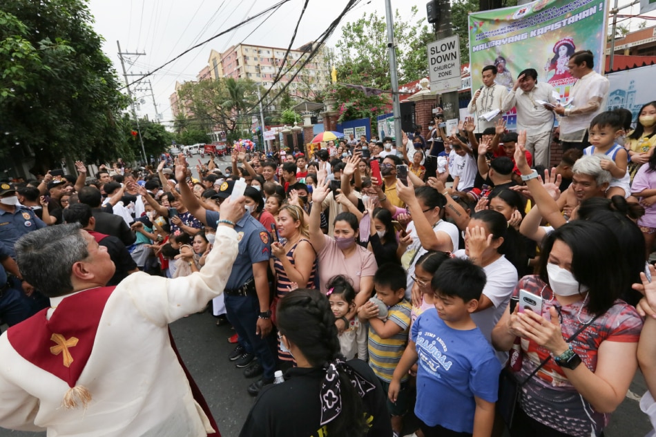 Residents raise their hands as a lay-person blesses them with holy water during the Buling-buling Festival in Pandacan, Manila on January 14, 2023. George Calvelo, ABS-CBN News
