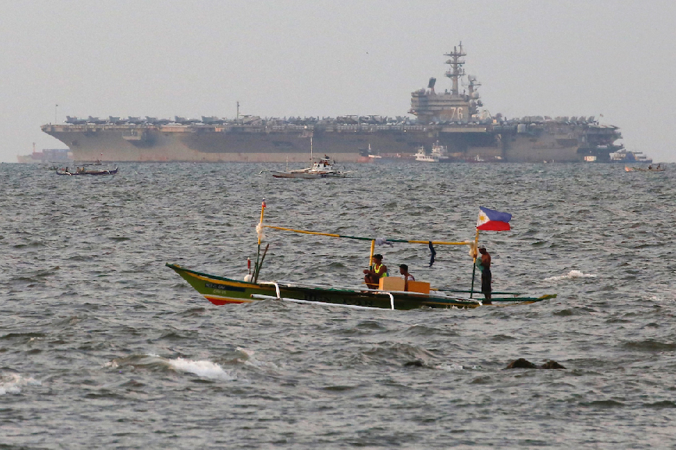 A local outrigger boat sails in Manila Bay as the USS Ronald Reagan (CVN-76) aircraft carrier is seen docked in the background on Oct. 14, 2022. The nuclear-powered ship, stationed in Japan as part of the US Navy's Seventh Fleet, conducts routine maritime exercises in the waters around Korea and Japan amid the tension with China and North Korea. Francis Malasig, EPA-EFE/File 