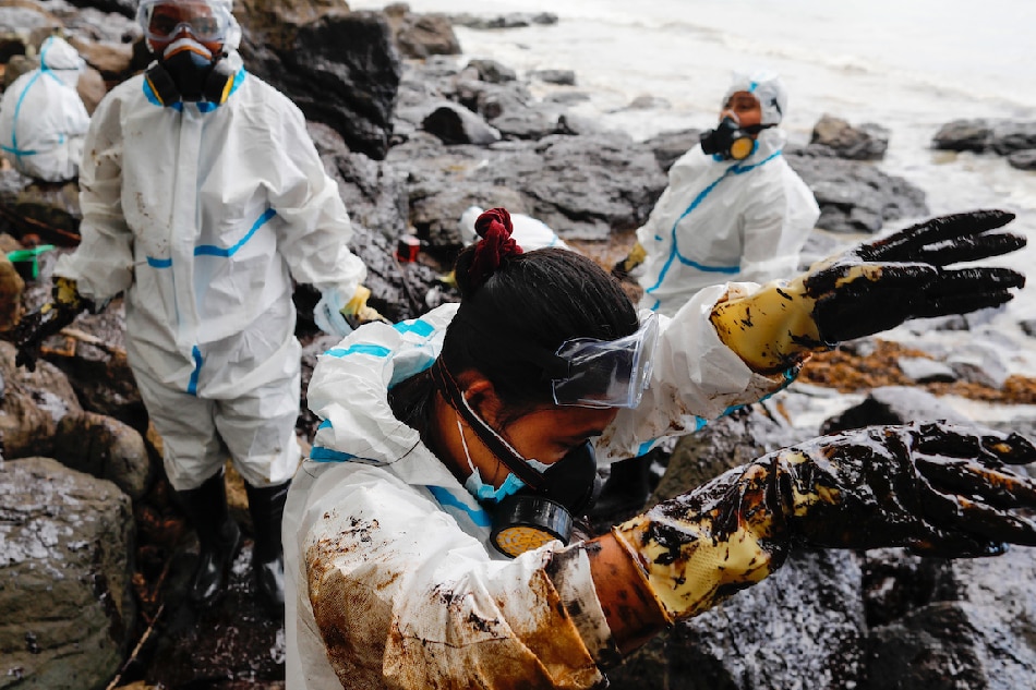 Filipino fishermen wearing protective suits collect oily waste along a beach in the coastal town of Pola, Mindoro island, March 6, 2023. Affected fisherfolk were tapped by the government to work in containing an oil spill that washed ashore in their villages. Francis Malasig, EPA-EFE