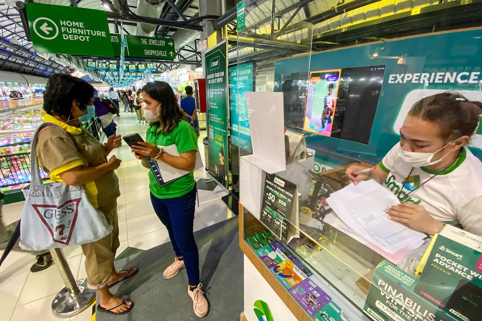 Sales representatives of telecommunications company assist clients in registering their prepaid SIM at the gadgets section in Greenhills Shopping Center in San Juan City on December 27, 2022. Jonathan Cellona, ABS-CBN News