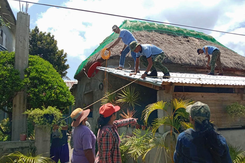 This undated handout photo received from Ivana Police station on Saturday shows police helping residents reinforce the roof of their homes in Ivana town, Batanes province, on the very tip of the Philippines, ahead of Typhoon Betty (international name Mawar) grazing the province. Ivana Police station, AFP
