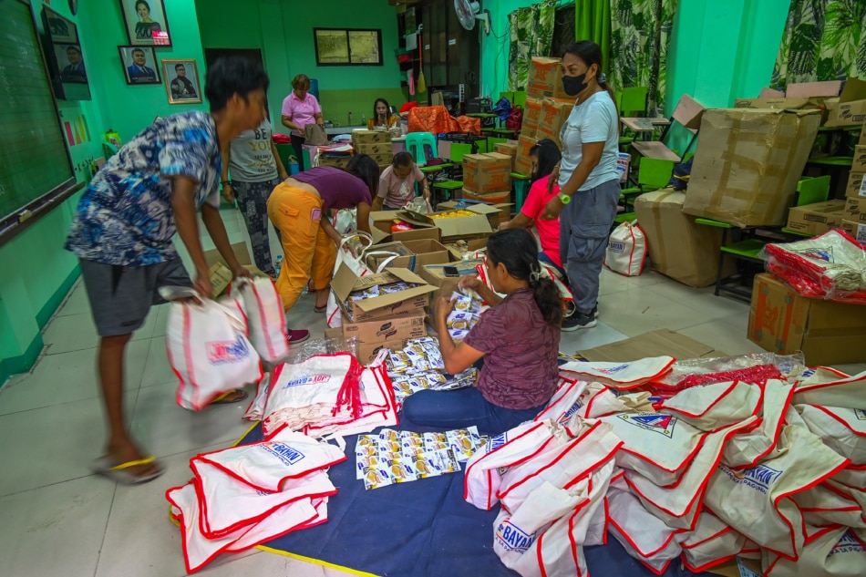 Barangay workers and volunteers repack relief goods consisting of canned goods, diapers, bottled water, noodles, sanitary kits, and rice at a daycare center in Barangay Bagong Silangan in Quezon City on May 27, 2023. Maria Tan, ABS-CBN News