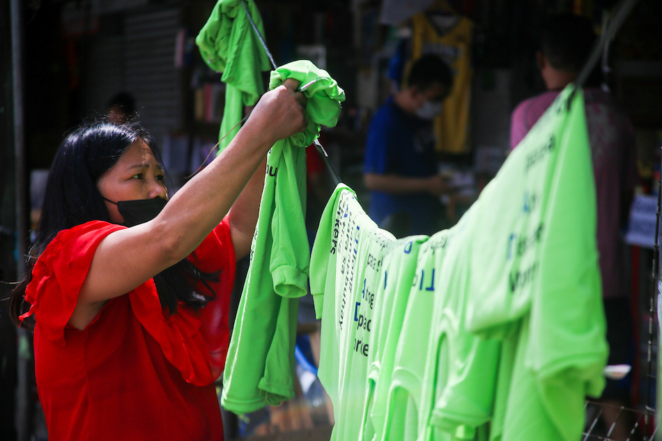 An employee of a silkscreen shop dries newly printed shirts to be given to recipients of the Department of Labor and Employment’s job creation program Tulong Panghanapbuhay sa Ating Disadvantaged/Displaced Workers (TUPAD) at a workshop in Manila on November 16, 2021. ABS-CBN News/file