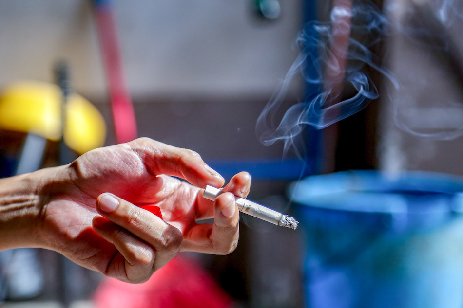 A man lights a cigarette outside a restaurant in Mandaluyong. George Calvelo, ABS-CBN News/File