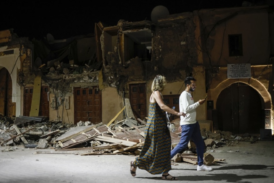 People pass by a damaged house in the old town of Marrakech, Morocco on Sept. 10, 2023. Yoan Valat, EPA/EFE