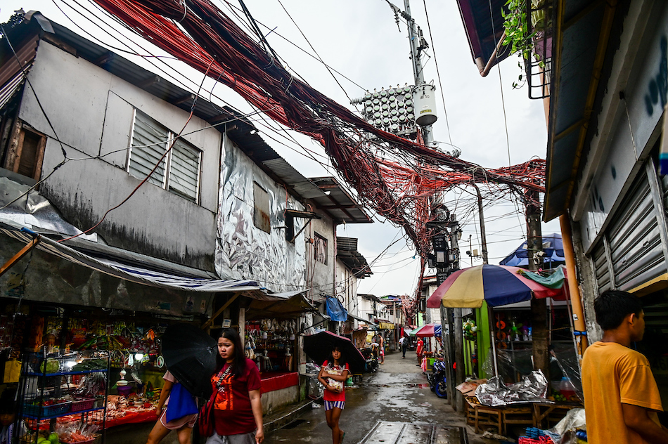 Electrical cables crisscross one another as electric meters hang on posts in Barangay Old Capitol, Quezon City on July 11, 2023. Maria Tan, ABS-CBN News