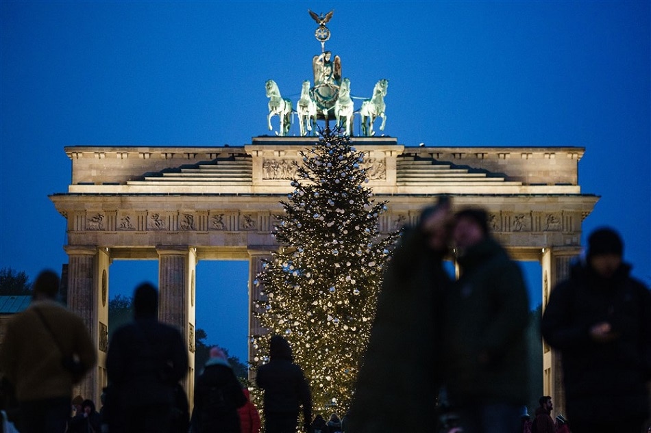 Passers-by stand in front of a Christmas tree at the Brandenburg Gate in Berlin, Germany, EPA-EFE/CLEMENS BILAN