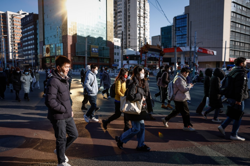 People wearing face masks walk in the business district of Beijing, China, Jan. 3, 2023. Scientists have warned China that the country will face multiple waves of COVID-19 infections as the omicron variant mutates to spread faster and evade immunity. Mark R. Cristino, EPA-EFE