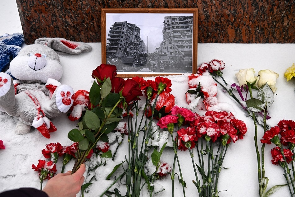 A person lays flowers in memory of those killed in the weekend strike on a residential block in the Ukrainian city of Dnipro, at the monument to famous Ukrainian poetess Lesya Ukrainka in Moscow on January 17, 2023. AFP Photo