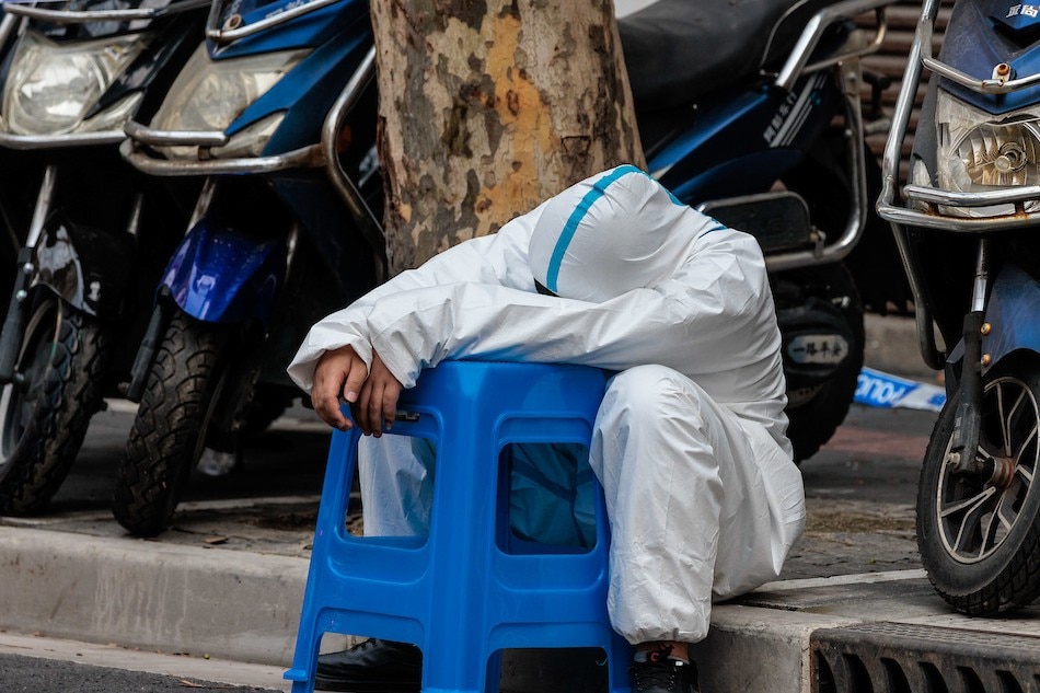 A health worker in protective gear rests at the entrance to a residential compound currently under COVID-19 quarantine in Shanghai, China, March 14, 2022. Alex Plavevski, EPA-EFE/File 