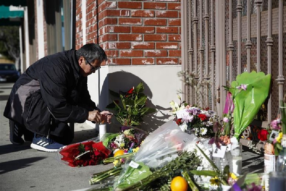 A person lights a candle at a makeshift memorial site in front of the Star Dance Studio in Monterey Park, California, USA, 23 January 2023. A 72-year-old man of Asian descent shot and killed 10 people as they celebrated the Lunar New Year at Star Dance Studio on 21 January 2023. EPA-EFE/CAROLINE BREHMAN