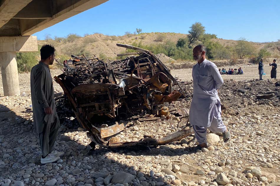 Residents look at the wreckage of a burnt passenger bus in Lasbela district of Pakistan's Balochistan province on January 29, 2023. - At least 40 people died when a bus plunged off a bridge in southwestern Pakistan and burst into flames, a government official said on January 29. Ismail Sasoli , AFP