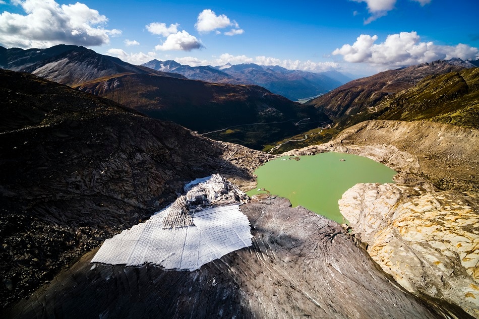 A lake of molten ice from the Rhone Glacier (right) and ice-protecting blankets (left) are pictured prior to a visit of the microorganism sample collection site of the Center for Changing Alpine and Polar Environments of the Ecole Polytechnique Federale de Lausanne (EPFL) in Obergoms, Switzerland, 13 September 2018. Valentin Flauraud, EPA-EFE/File