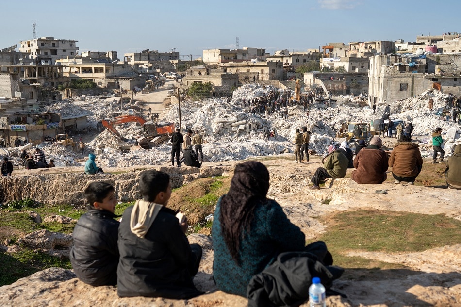 People watch rescuers and volunteers search for survivors under the rubble of collapsed houses, in Harim town near Idlib, Syria, 08 February 2023. Karam Al-Masri, EPA-EFE.