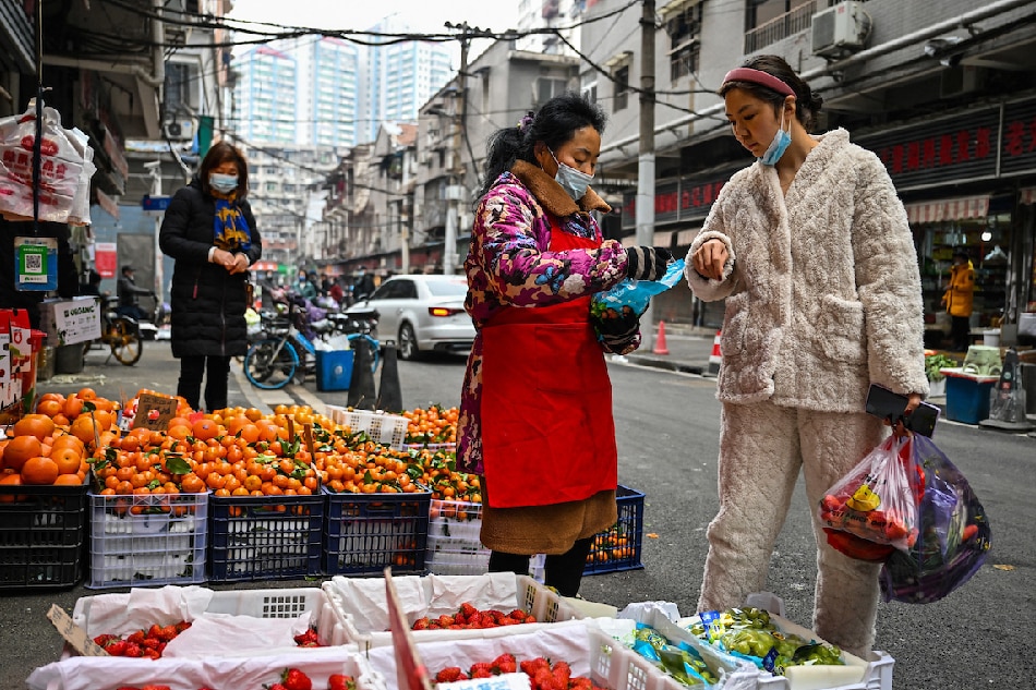 A customer (right) buys fruit at a local market in Wuhan, in China's central Hubei province, on Jan. 23, 2023. Hector Retamal, AFP