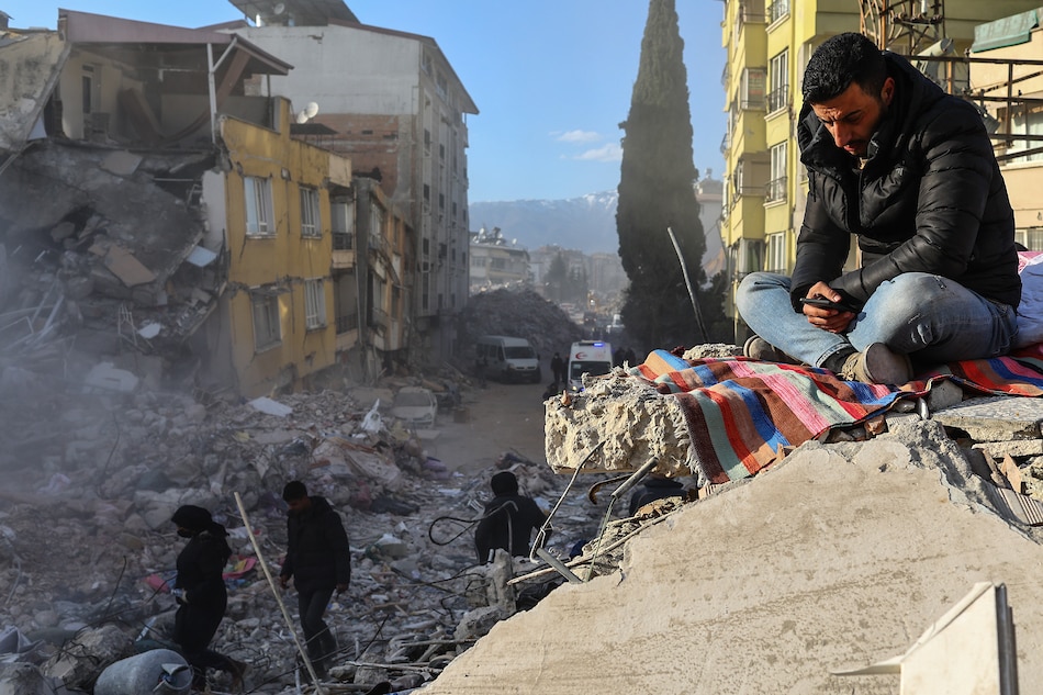 A man standing on debris while rescuers work at the site of collapsed buildings after a powerful earthquake, in Hatay, Turkey on February 15, 2023. Sedat Suna, EPA-EFE