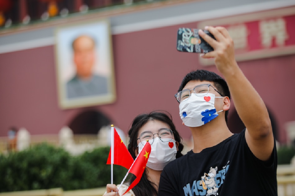 A couple holding Chinese flags take souvenir photos in front of the rostrum of Tiananmen on Chinese National Day, in Beijing, China, 01 October 2022. The 'National Day Golden Week' begins on 01 October when most of the people in China have a seven-day national holiday. EPA-EFE/WU HAO