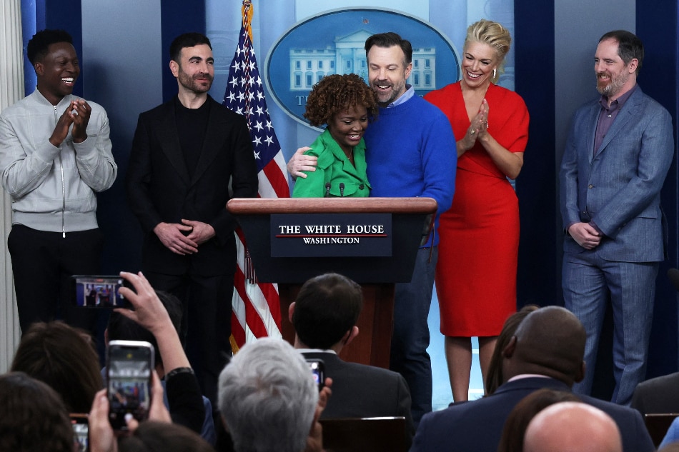 Comedian Jason Sudeikis of the Apple TV+ comedy series Ted Lasso embraces White House Press Secretary Karine Jean-Pierre as other cast members (L-R) Toheeb Jimoh, Brett Goldstein, Hannah Waddingham and Brendan Hunt look on during a White House daily news briefing at the James S. Brady Press Briefing Room on March 20, 2023 in Washington, DC. Alex Wong, AFP