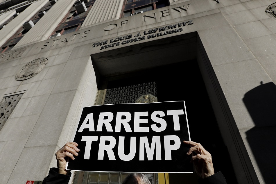 A protester holds up sign outside the New York State Louis Lefkowitz office building where grant jury testimony is being heard in the possible indictment of Former President Donald Trump, in New York, New York, USA, March 20, 2023. Peter Foley, EPA-EFE.