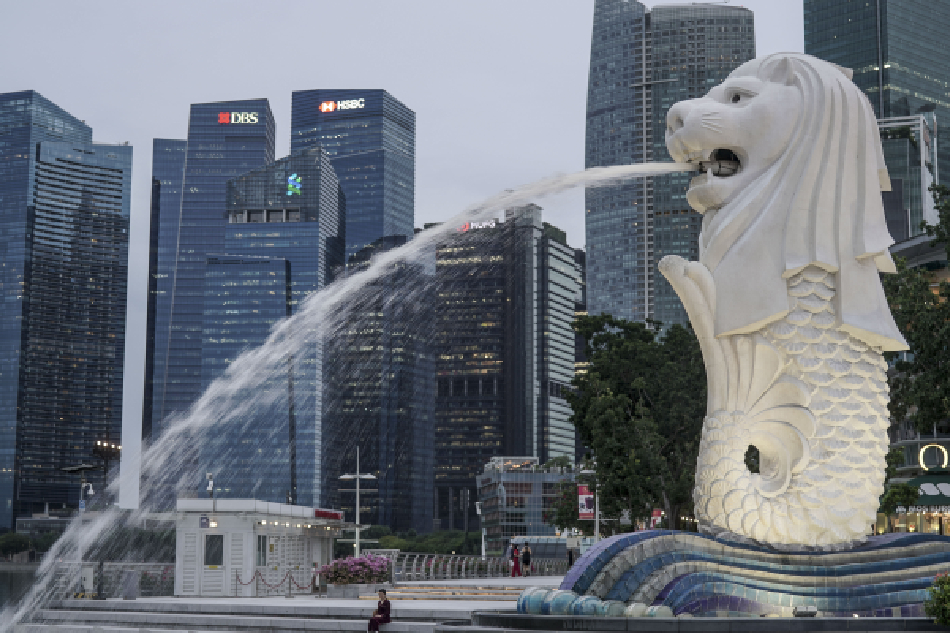  A woman is dwarfed by the Merlion statue and buildings of the financial district in Singapore on July 14, 2021. Wallace Woon, EPA-EFE/File