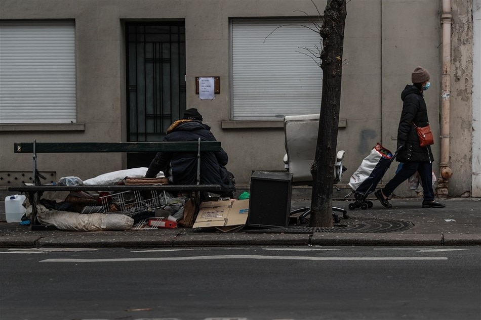 A woman walks by a homeless person in the 15th district of Paris, France, 03 April 2020. File/ Mohammed Badra, EPA-EFE