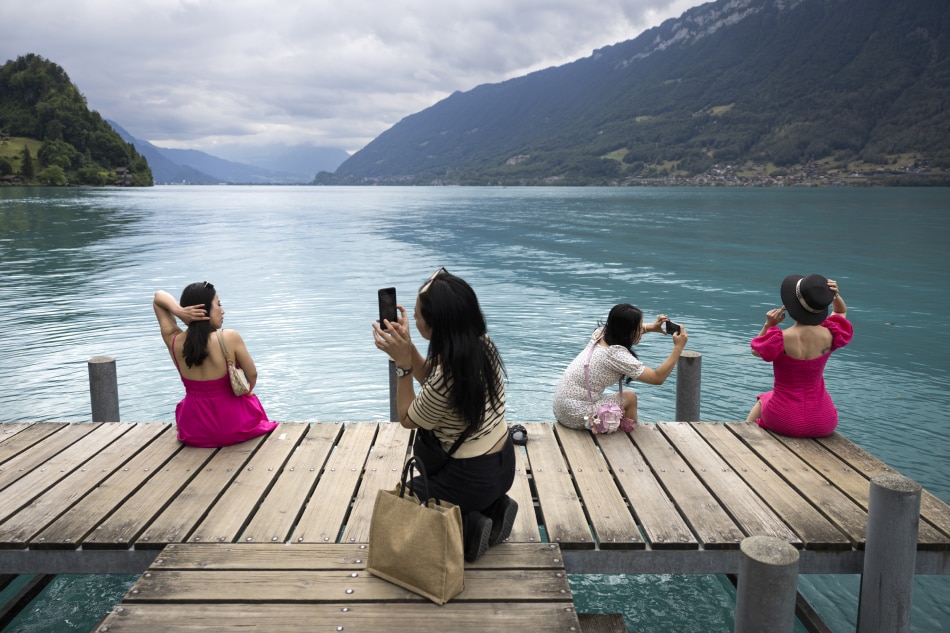 Vietnamese visitors take pictures at the pier in Iseltwald, Switzerland, July 26, 2022. Lots of Asian TV fans and tourists visit the place because the romantic Korean Netflix drama 'Crash Landing On You' was filmed in the Interlaken region of Switzerland, with key scenes set on Iseltwald's picturesque pier as well as nearby Sigriswil and Lungern. Peter Klauner, EPA-EFE/File