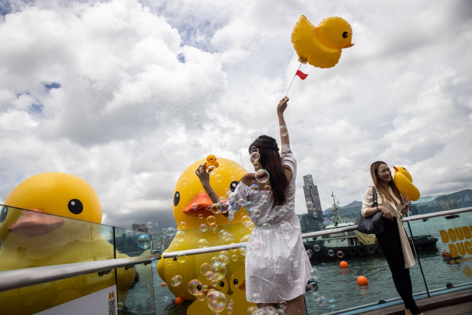 People pose with two large inflatable yellow ducks called Double Duckî by Dutch artist Florentijn Hofman in Victoria Harbour in Hong Kong on June 9, 2023. Isaac Lawrence, AFP