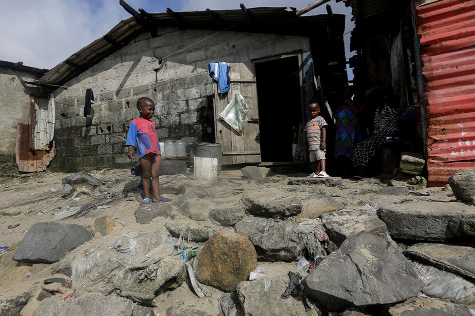 Children walk on rocks placed in front of a home in the West Point coastal slum community in Monrovia, Liberia, October 23, 2021 (issued October 25, 2021). Ahmed Jallanzo, EPA-EFE/File