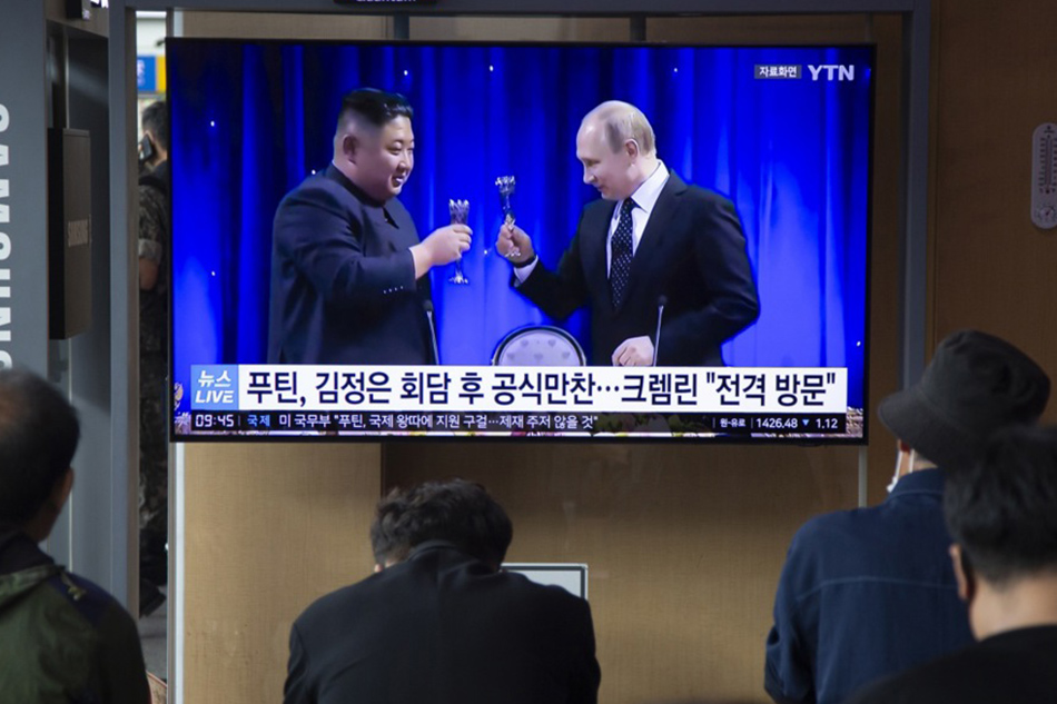 People watch a news segment detailing North Korean Leader Kim Jong-un