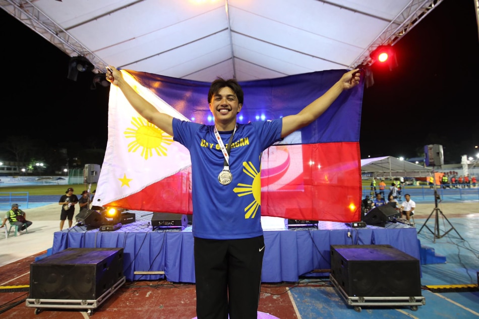 Elijah Cole drapes the Philippine flag over his shoulders after winning his nerve-wracking duel with Hokett delos Santos in the men's pole vault. PATAFA