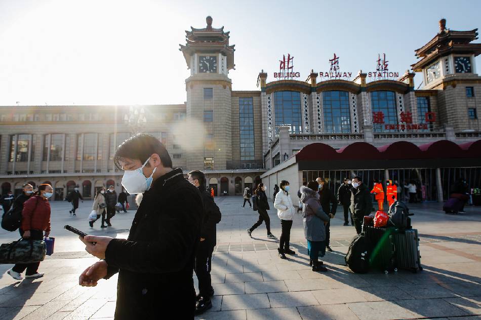 Passengers wearing face masks walk with their luggage in front of the Beijing Railway Station in Beijing, China on Jan. 10, 2023. Wu Hao, EPA-EFE